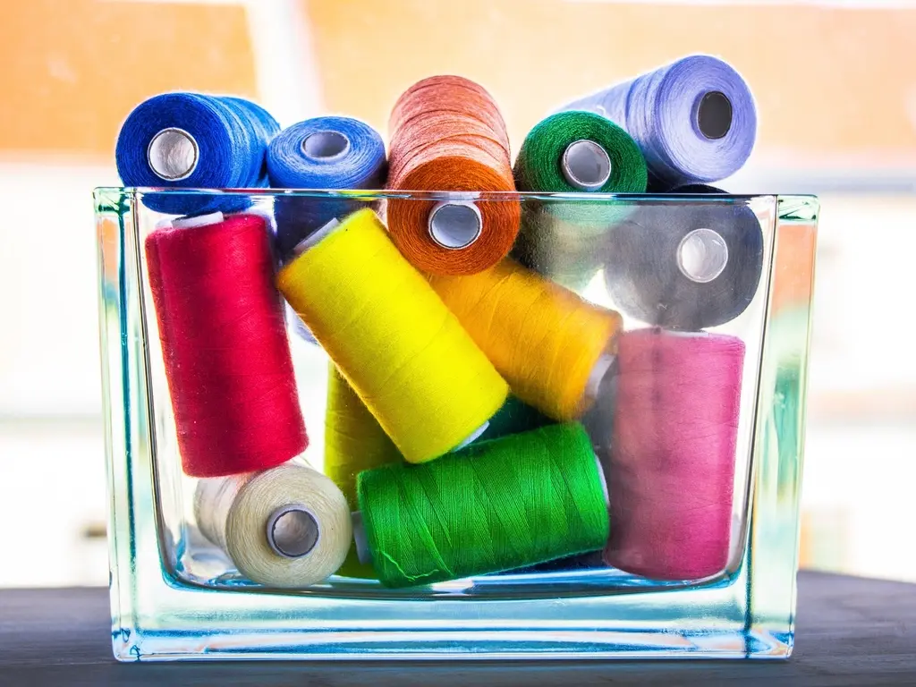 Colourful embroidery thread spools in a glass jar